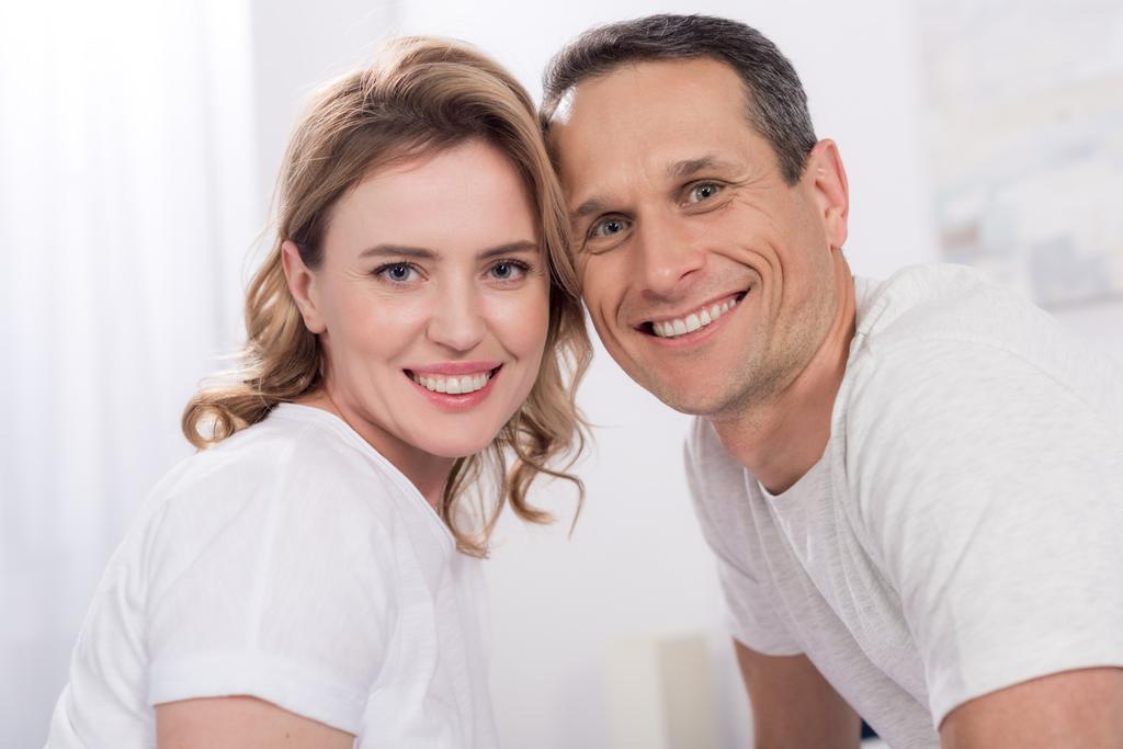 portrait of happy couple looking at camera at home - Photo, Image