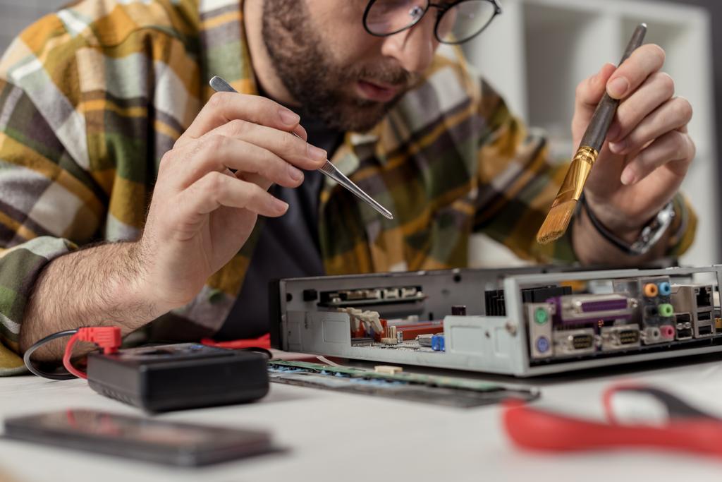 homem usando multímetro e batedor durante a fixação placa-mãe computador
 - Foto, Imagem