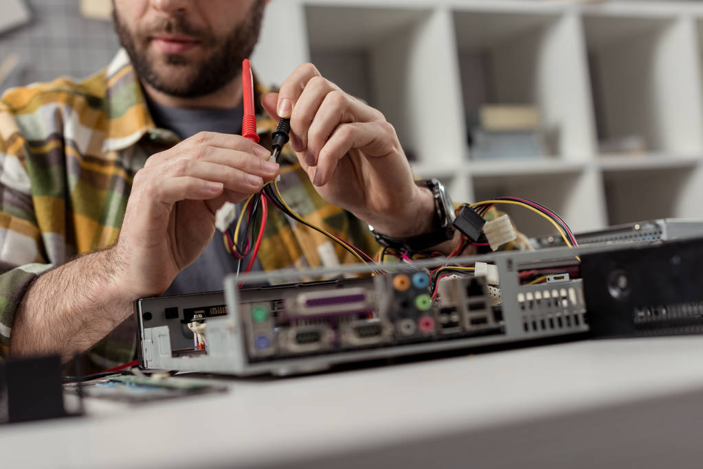 cropped image of man holding wires in hands while fixing computer  - Photo, Image