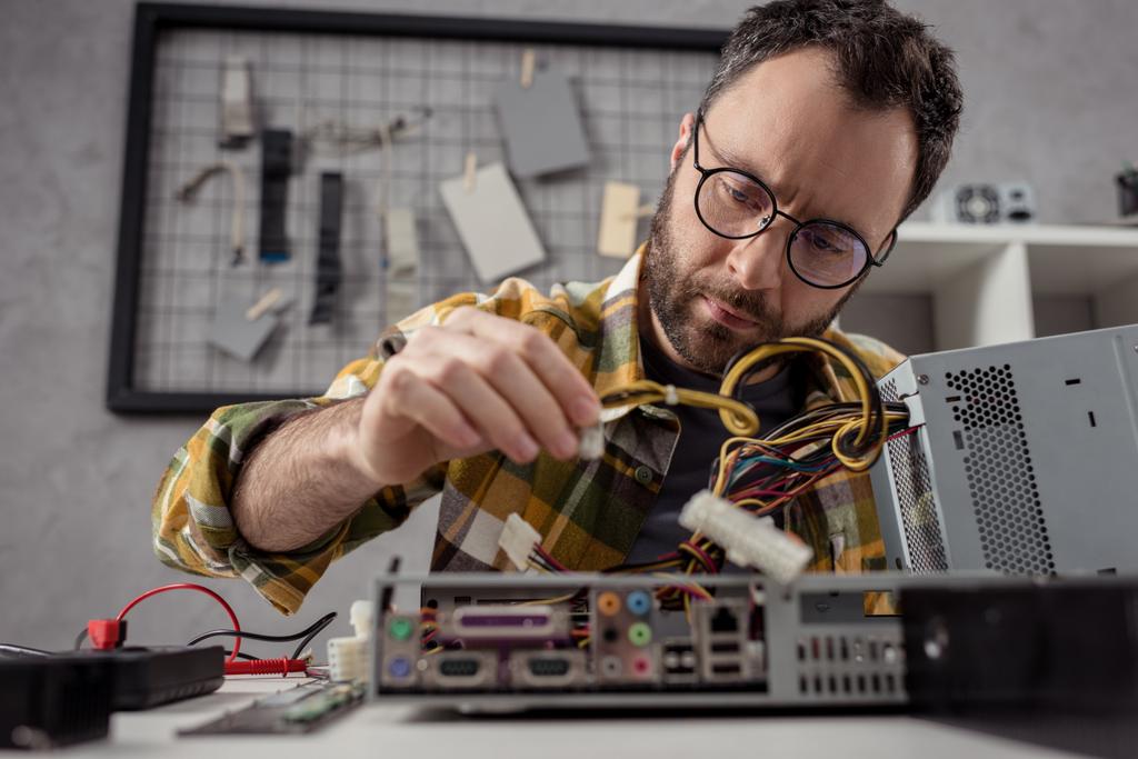 hombre ajustando los detalles mientras que fija el ordenador
      - Foto, Imagen