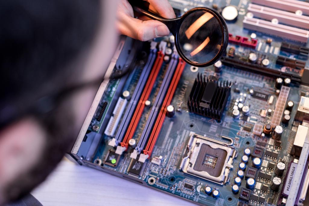 cropped image of man using magnifier while fixing motherboard - Photo, Image
