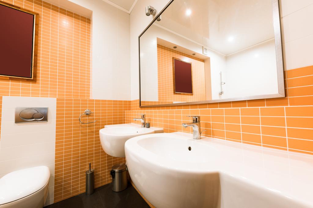 Nahaufnahme des modernen Badezimmers in orangen und weißen Farben - Foto, Bild