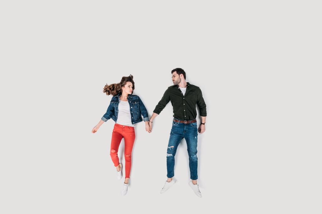 pohled shora stylový šťastnému páru drží za ruce, izolované na bílém - Fotografie, Obrázek