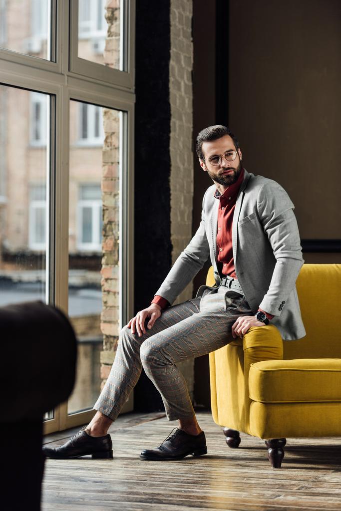 stijlvolle man in grijs pak die zich voordeed bij raam  - Foto, afbeelding