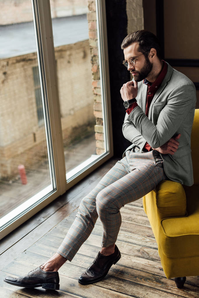 στοχαστικός άνθρωπος σε μοντέρνο κοστούμι κάθεται στο παράθυρο  - Φωτογραφία, εικόνα