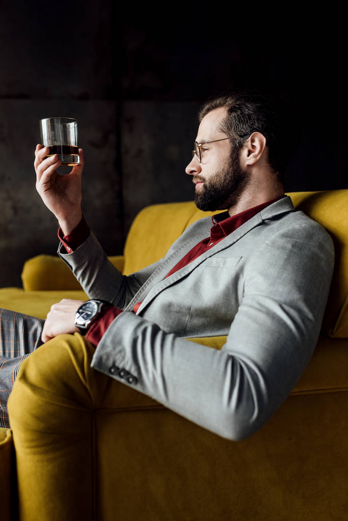 bearded handsome man looking at glass of whiskey   - Photo, Image