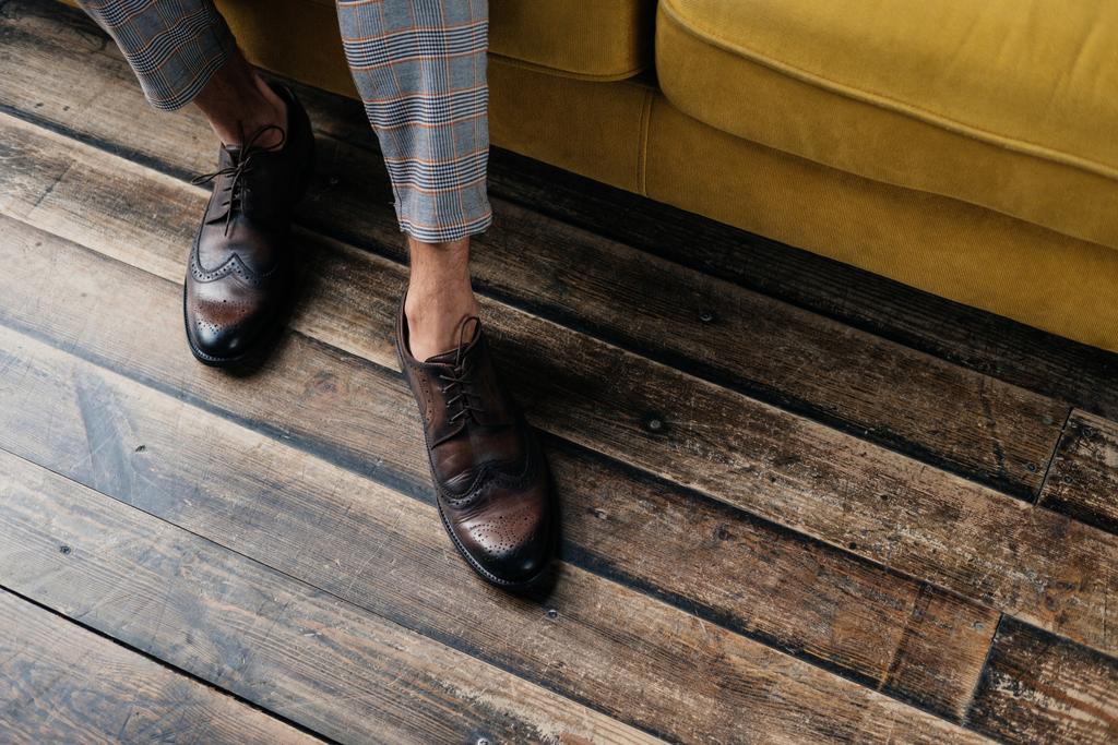 vista recortada de elegante hombre con estilo en zapatos brogue de pie en el sofá
 - Foto, imagen