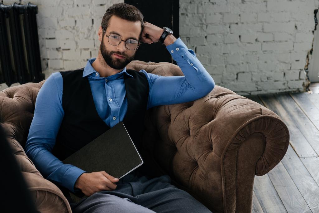 бородатый задумчивый бизнесмен держит ноутбук и сидит в кресле
 - Фото, изображение