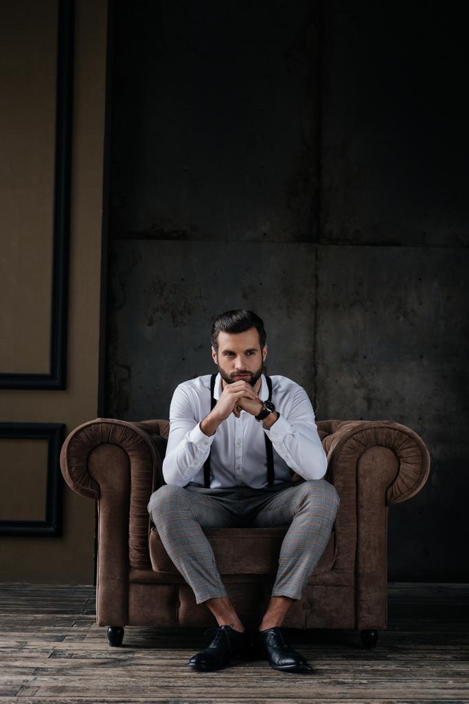 pěkný stylový muž myšlení a sedí v křesle - Fotografie, Obrázek