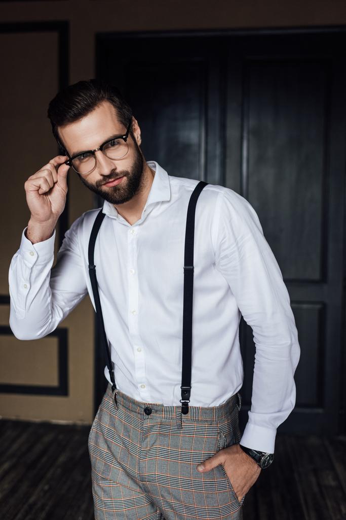 модний чоловік позує в окулярах, білій сорочці і підтяжках
  - Фото, зображення