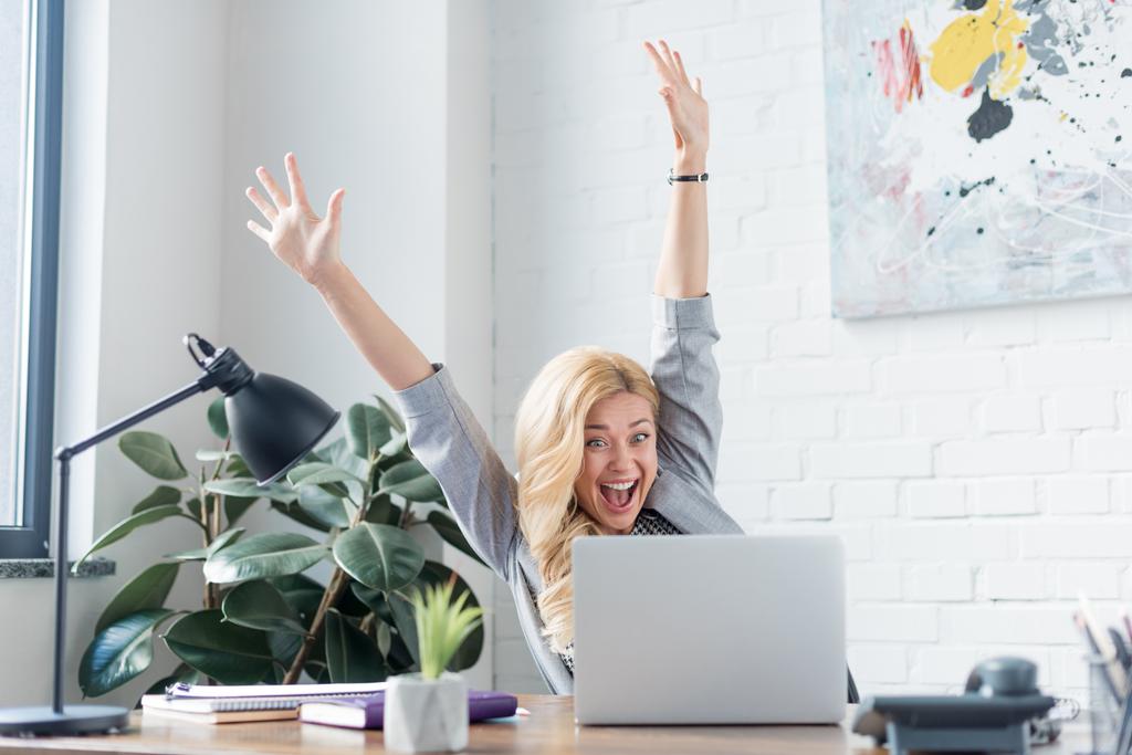 mulher de negócios feliz gritando com as mãos para cima e olhando para laptop
 - Foto, Imagem