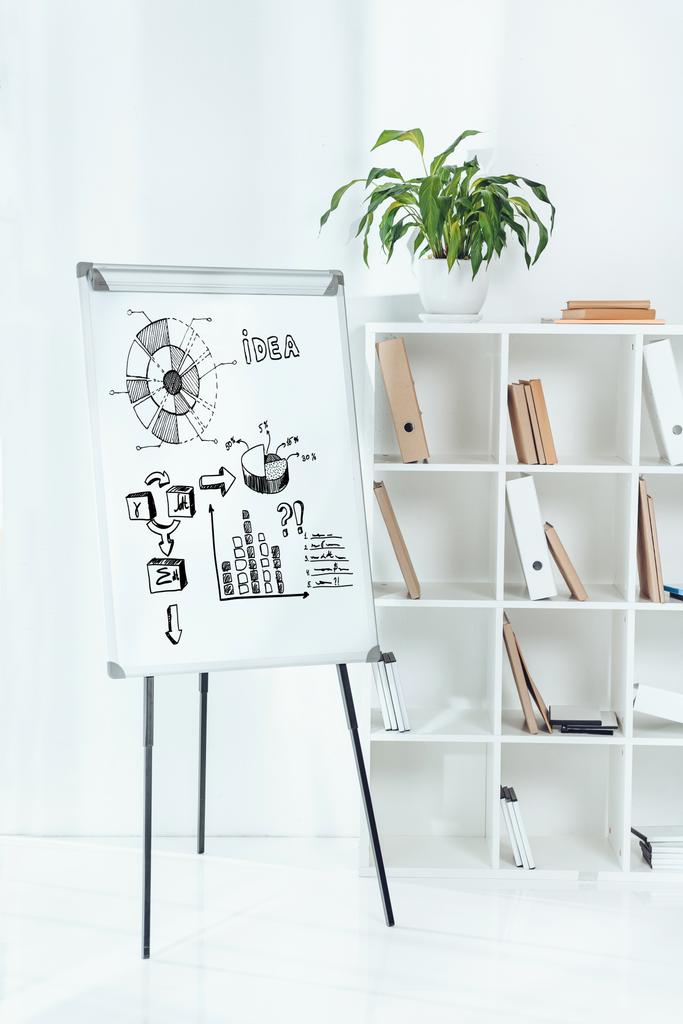 quadro branco com ícones de ideia de negócios e prateleiras de madeira com pastas no escritório
 - Foto, Imagem