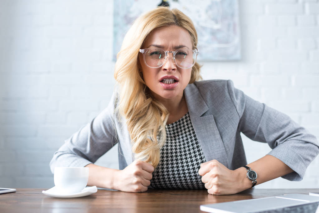 Irritierte Geschäftsfrau blickt mit Fäusten in Kamera - Foto, Bild