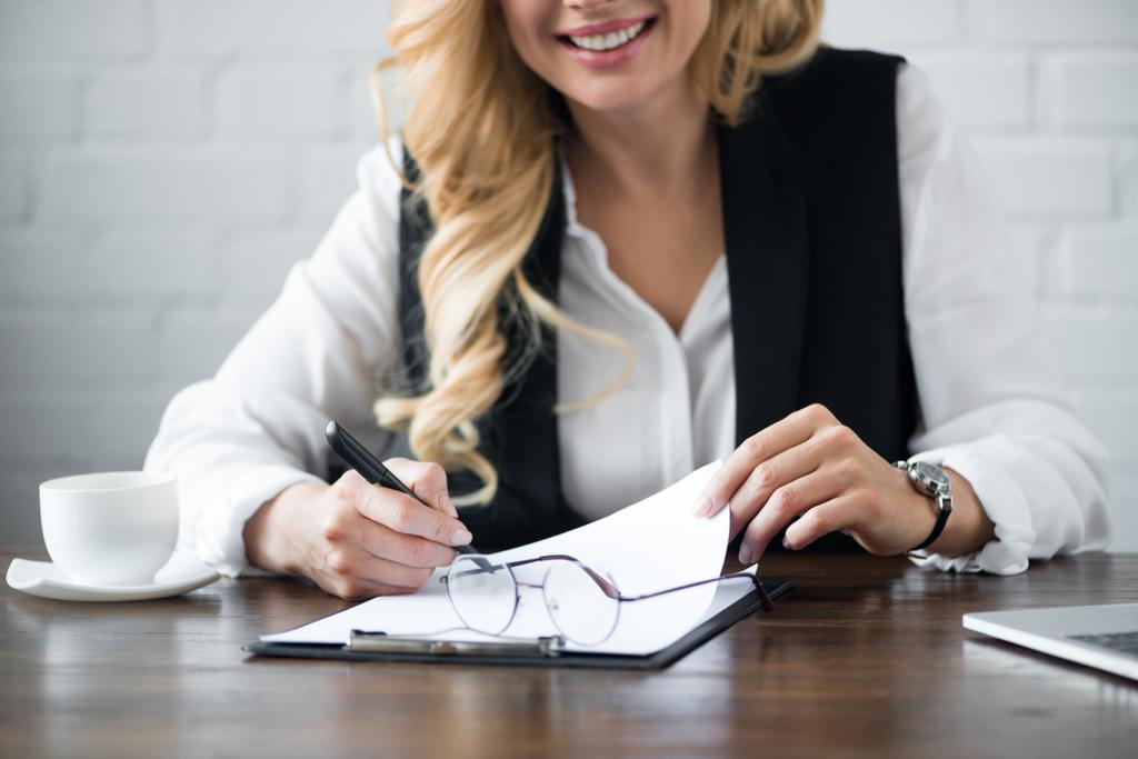 cropped image of businesswoman writing something to clipboard at office - Photo, Image