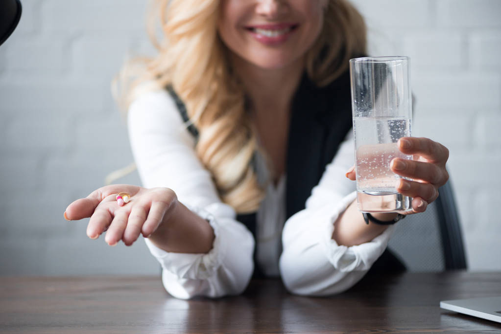 imagem cortada de empresária feliz segurando pílulas e vidro de água
 - Foto, Imagem