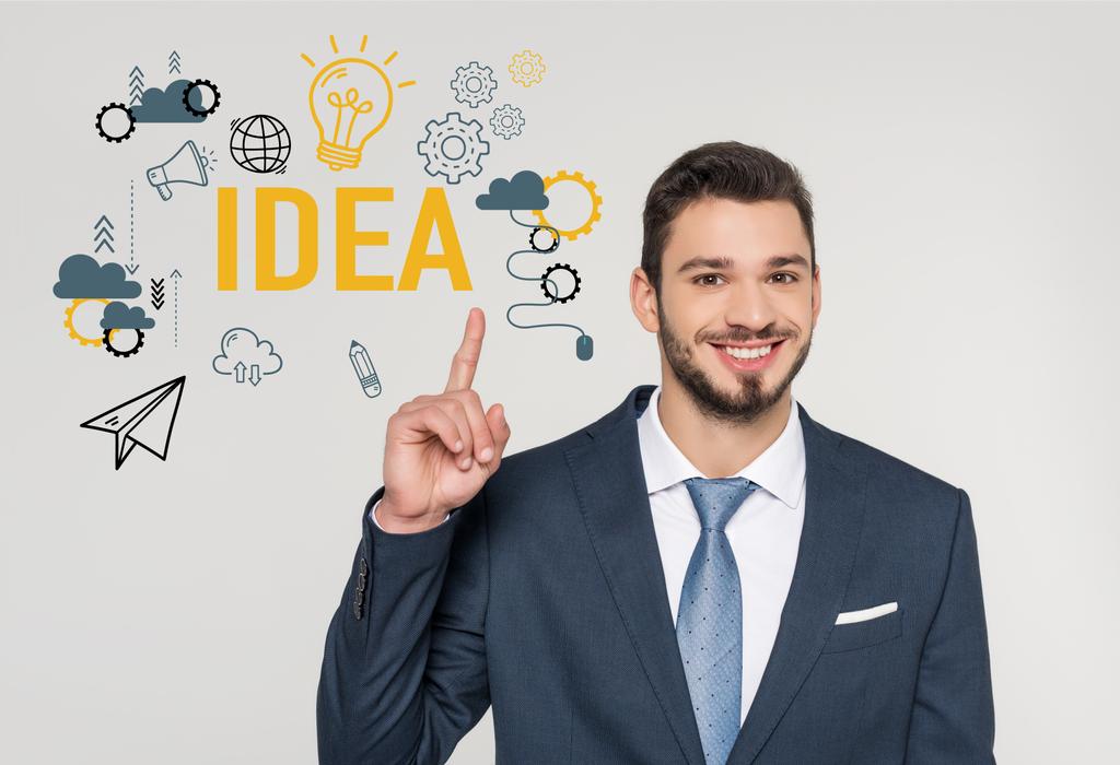 smiling young businessman pointing up with finger and looking at camera, idea concept  - Photo, Image