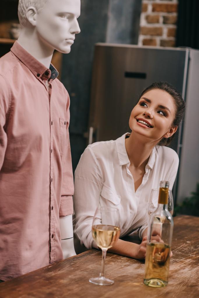 улыбающаяся женщина, глядя на манекен за столом с бокалами вина дома, идеальная концепция сон отношений
 - Фото, изображение