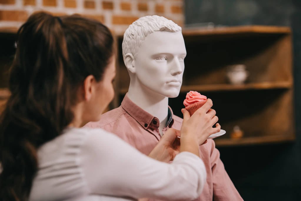 woman pretending to feed mannequin with cupcake at home, perfect relationship dream concept - Photo, Image