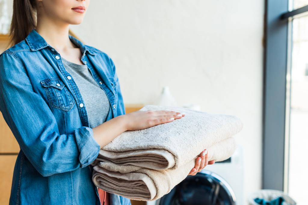 ritagliato colpo di giovane donna in possesso di asciugamani puliti a casa
 - Foto, immagini