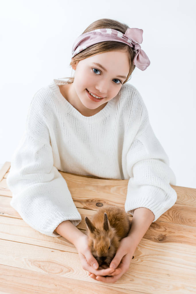 schöne kleine Mädchen lächelt in die Kamera, während sie niedliche pelzige Kaninchen hält - Foto, Bild