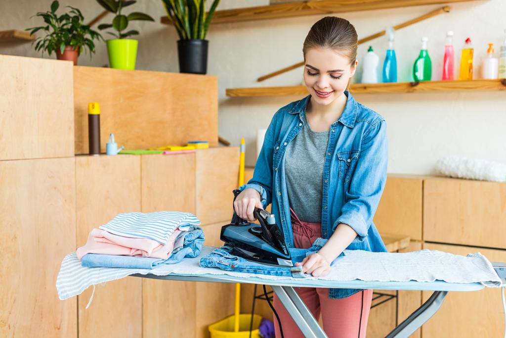 beautiful smiling young woman ironing clothes at home  - Photo, Image