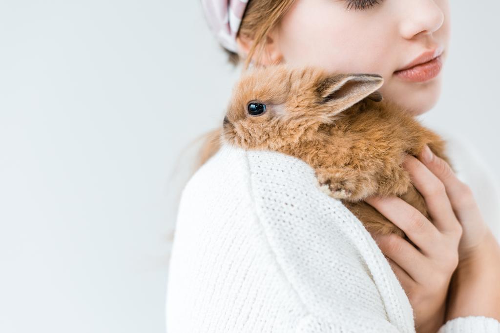 白で隔離かわいい毛皮のようなウサギを抱いた子供のクロップ撮影 - 写真・画像