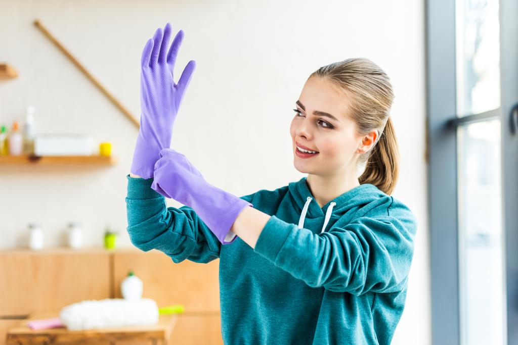 belle jeune femme souriante portant des gants en caoutchouc lors du nettoyage de la maison
  - Photo, image