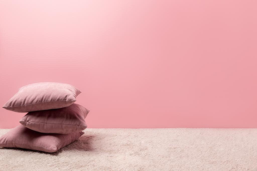 stack of pillows on carpet in front of pink wall - Photo, Image