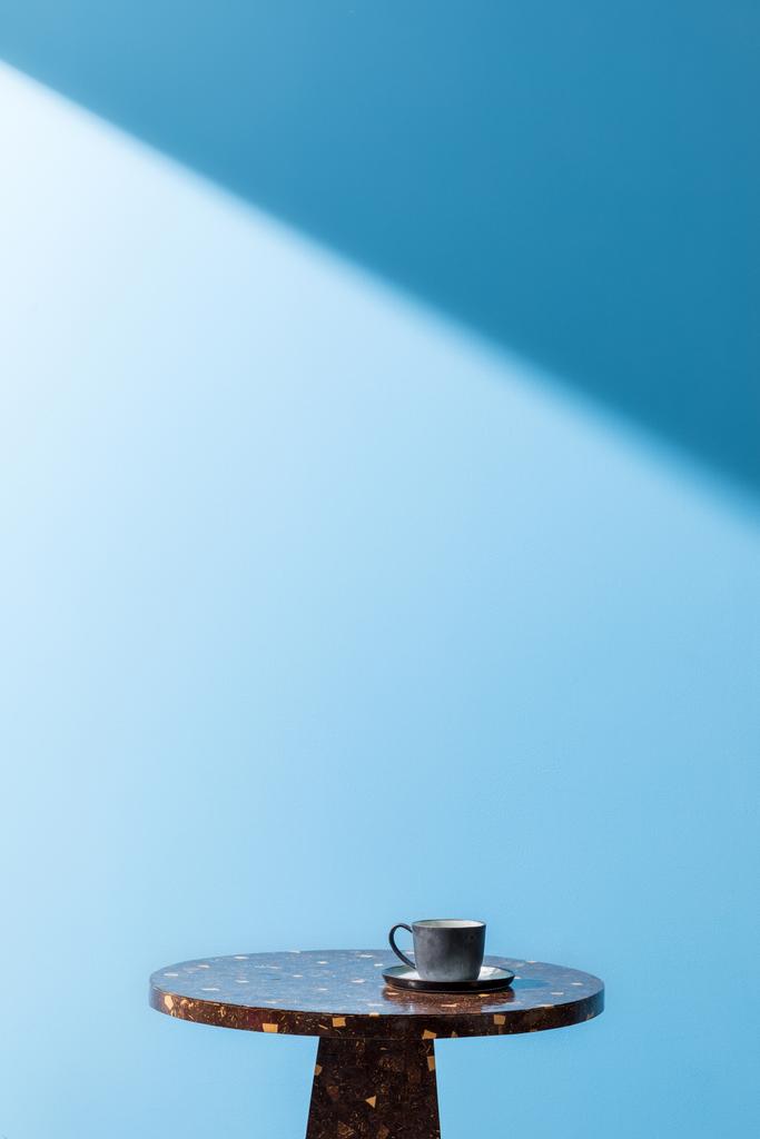 cup on coffee table in front of blue wall - Photo, Image