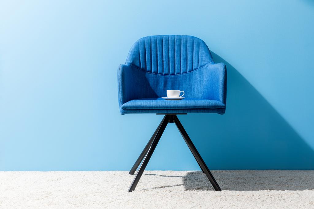 filiżankę kawy na krześle przed niebieską ścianą - Zdjęcie, obraz