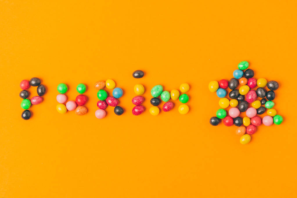 верхний вид пурим буквы из конфет и звезды изолированы на оранжевый
 - Фото, изображение