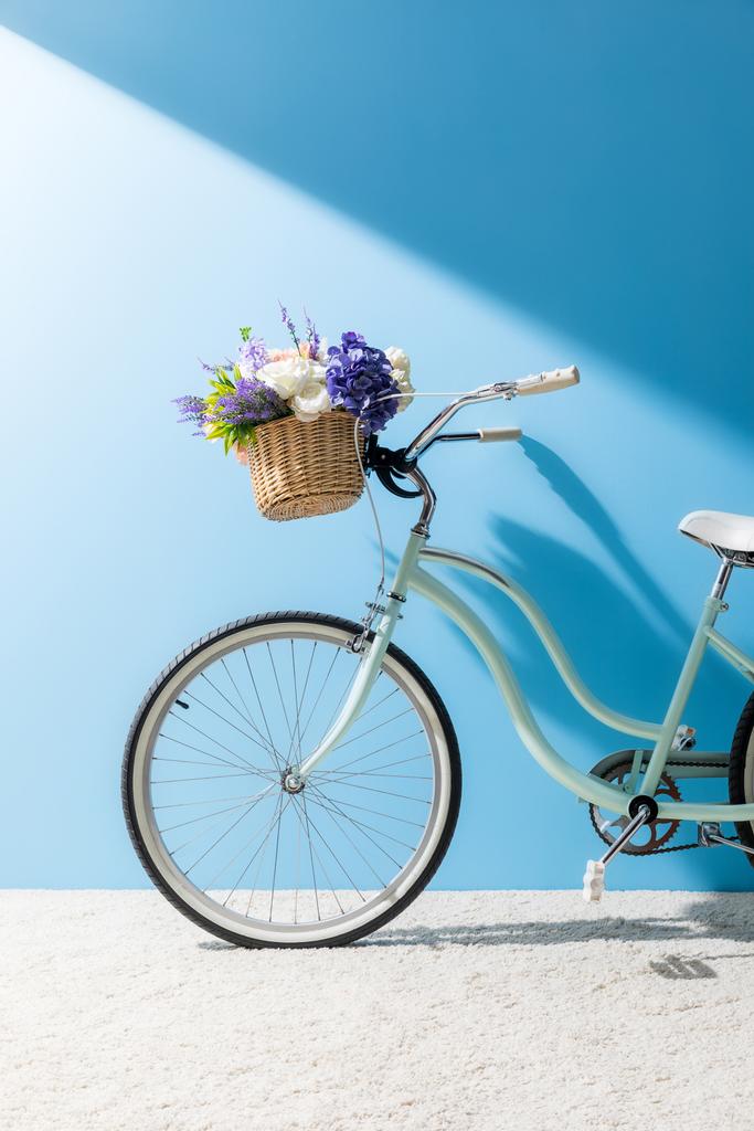 bicycle with beautiful flowers in basket in front of blue wall - Photo, Image