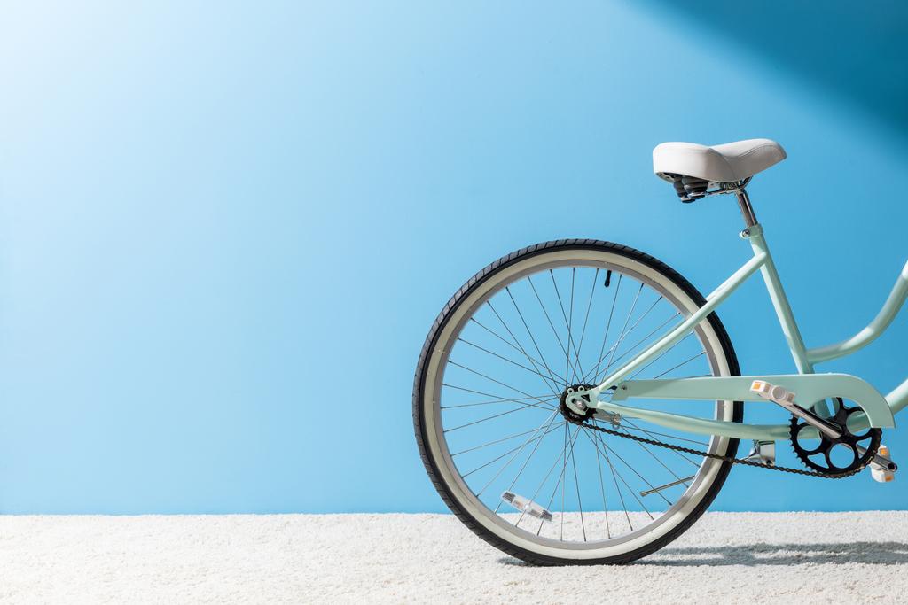 Hinterrad des Fahrrads steht auf Teppich vor blauer Wand - Foto, Bild