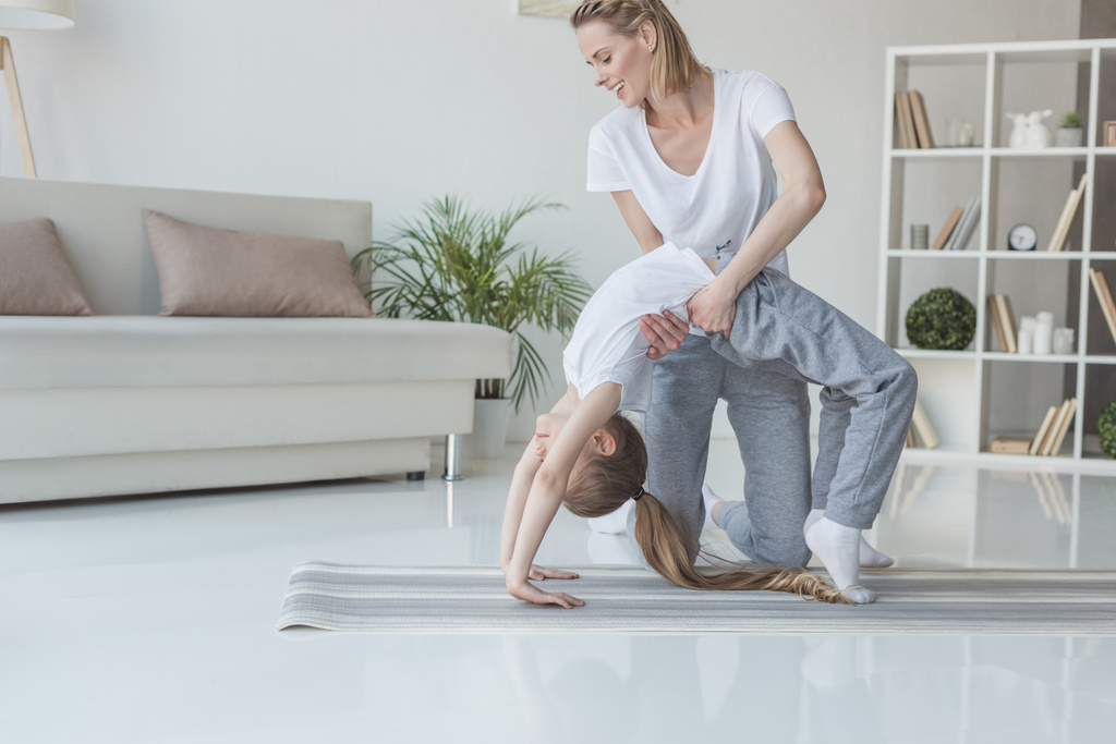 Szczęśliwa matka uczy córkę stanąć koło jogi w domu - Zdjęcie, obraz