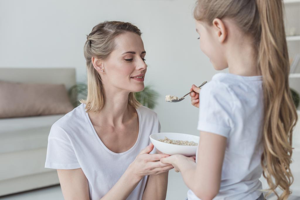 filha alimentando sua mãe com refeição de cereais em casa
 - Foto, Imagem
