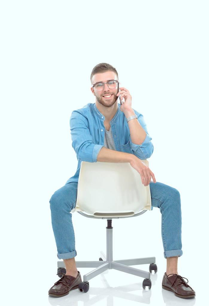 Νεαρός κάθεται σε καρέκλα και να χρησιμοποιούν κινητό τηλέφωνο. Startupper. Νέος επιχειρηματίας. - Φωτογραφία, εικόνα