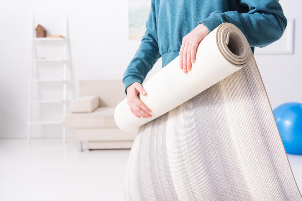 обрізане зображення дівчини, що скручує йога килимок вдома
 - Фото, зображення
