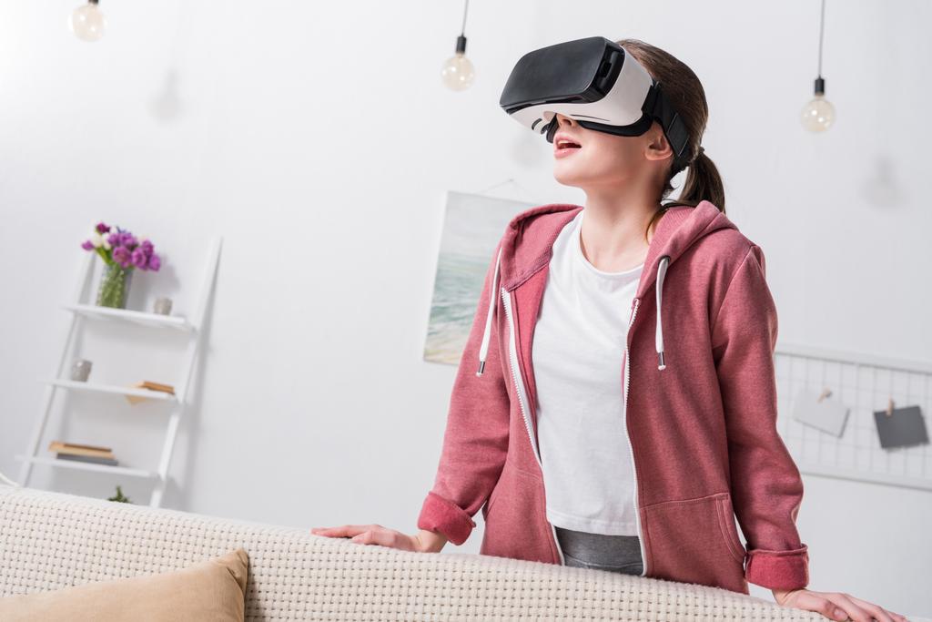 verrast meisje kijken iets met virtual reality headset thuis - Foto, afbeelding