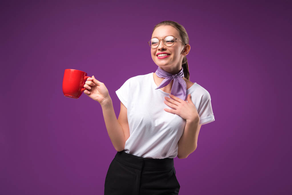 smiling girl posing with red cup of coffee isolated on purple - Photo, Image
