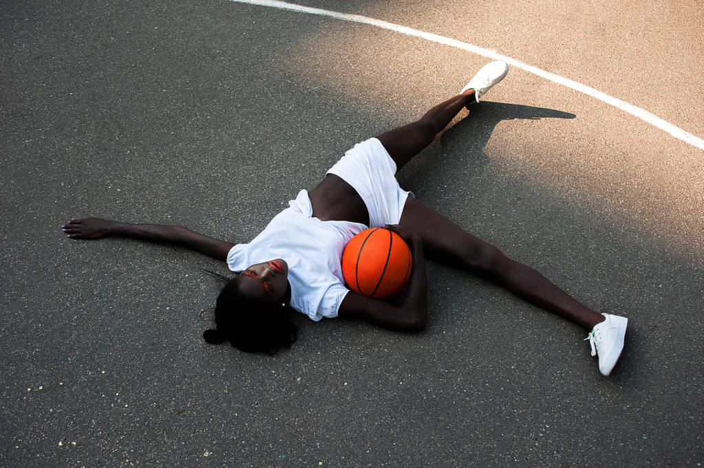 Sporty afro-american model in white with basketball on asphalt - Photo, Image
