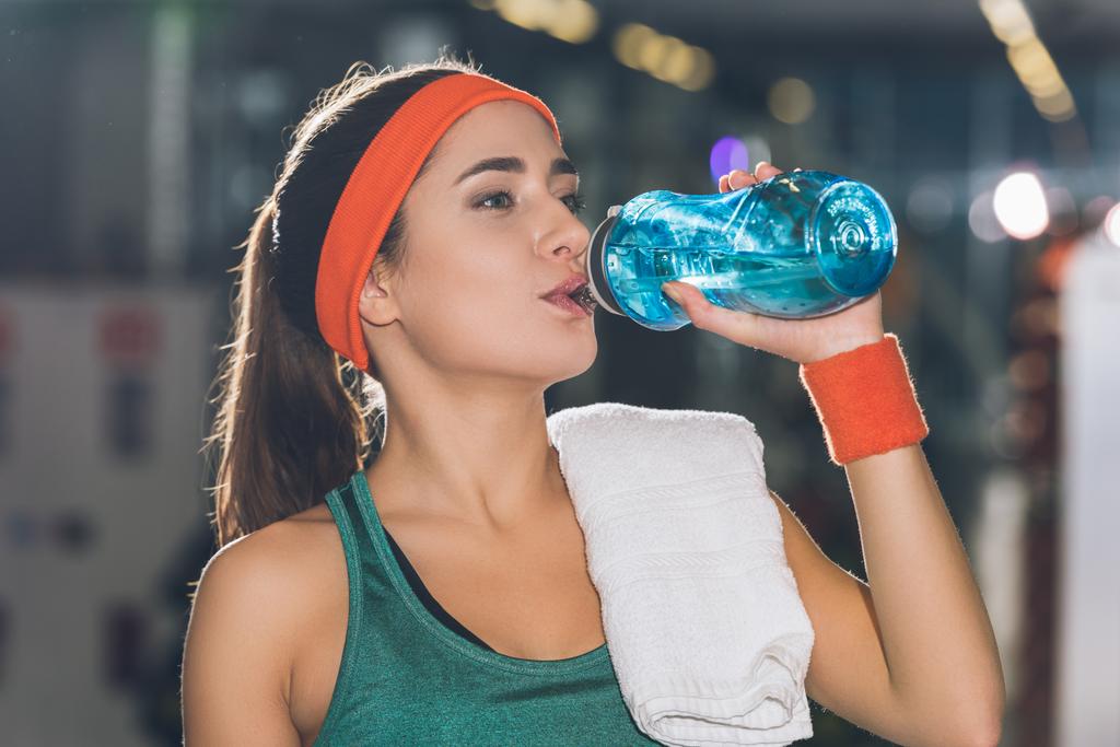 sporty woman drinking water at gym - Photo, Image