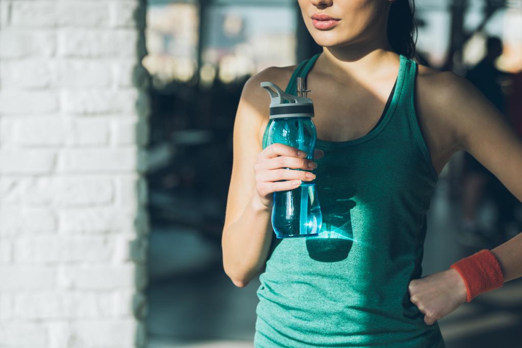 image recadrée d'une femme sportive tenant une bouteille d'eau
  - Photo, image