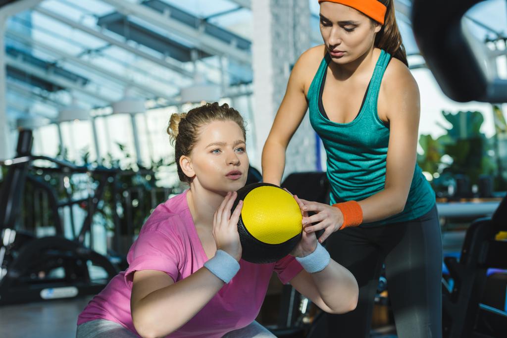 Übergewichtige Frau trainiert mit Medizinball, während Trainer sie beobachtet - Foto, Bild