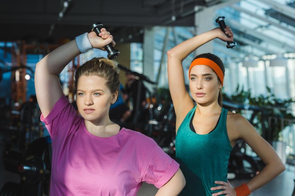Mujeres deportivas y con sobrepeso entrenando con pesas en el gimnasio
 - Foto, imagen