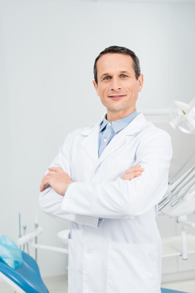 Médico confiante com braços dobrados na clínica odontológica moderna
 - Foto, Imagem