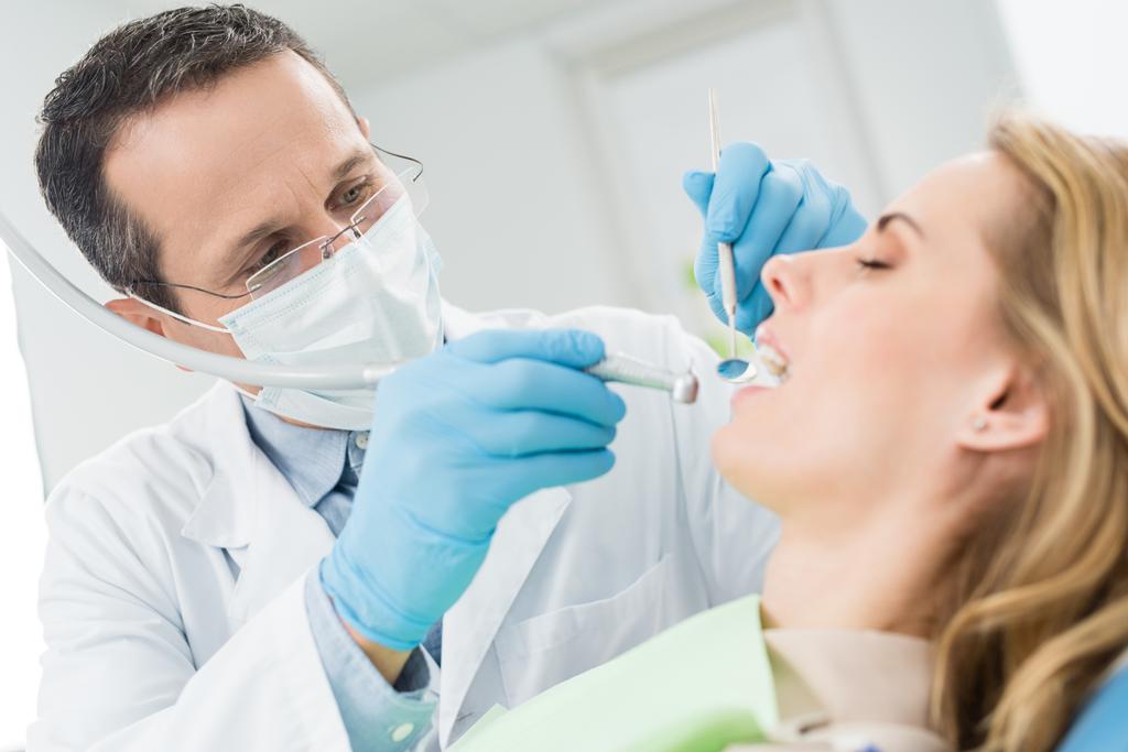 医者がモダンな歯科医院で患者の歯を治療します。 - 写真・画像