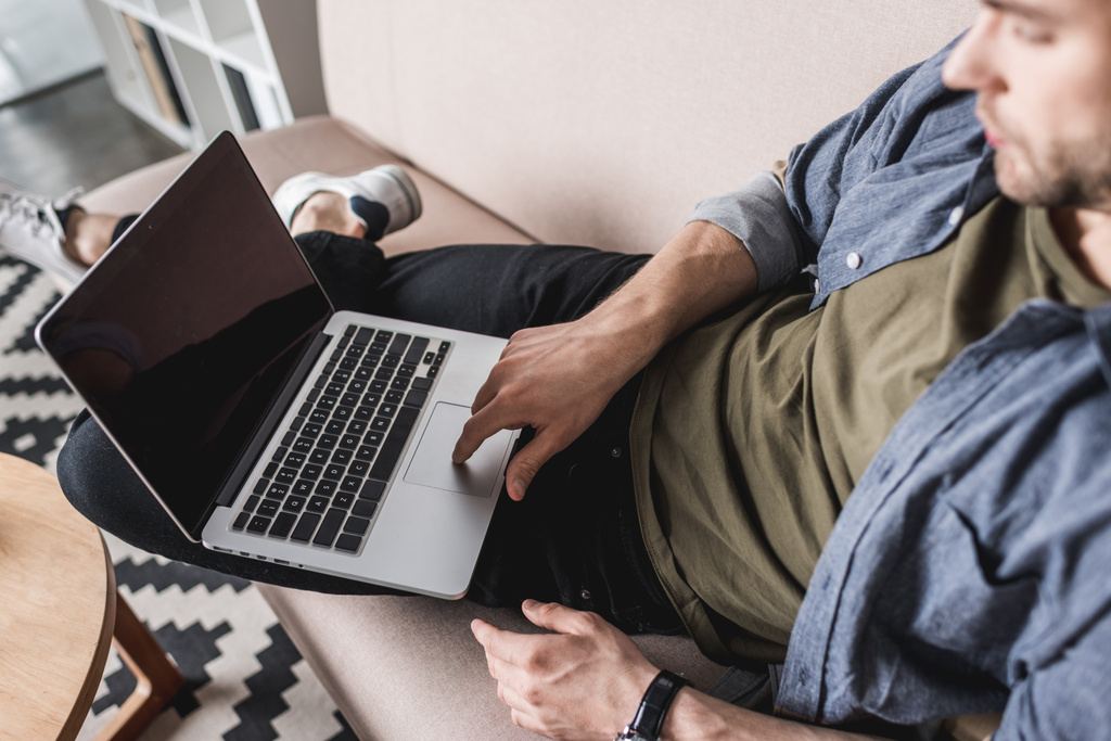 γκρο πλαν βολή του όμορφος άνθρωπος που εργάζονται με το laptop στον καναπέ - Φωτογραφία, εικόνα