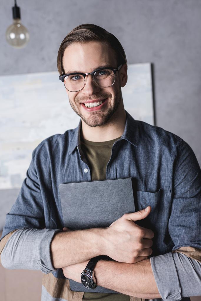 lachende jongeman in brillen houden boek - Foto, afbeelding