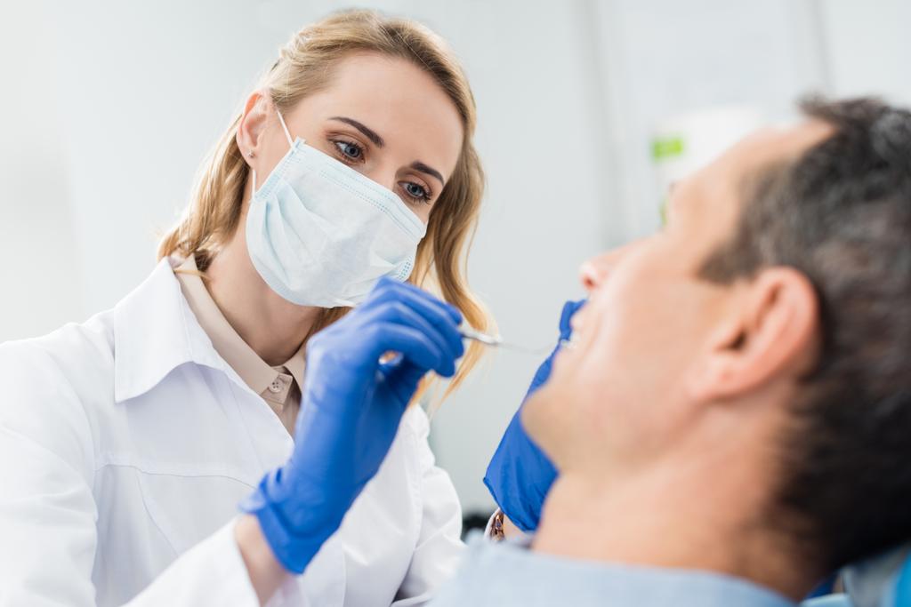 Arzt überprüft Patientenzähne mit Spiegel in moderner Zahnklinik - Foto, Bild