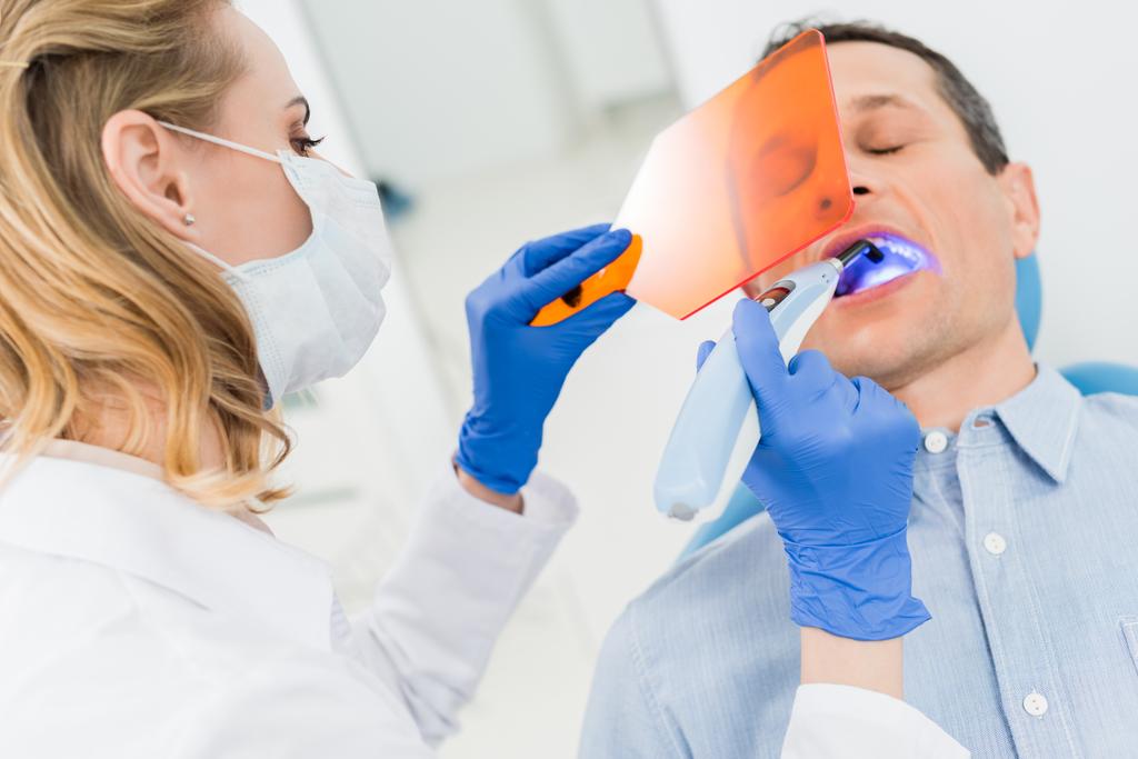 Za pomocą lampy uv w leczeniu zębów pacjenta w nowoczesny gabinet stomatologiczny dentysta - Zdjęcie, obraz
